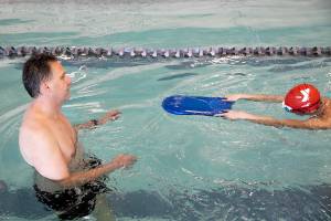 Tom Wunderlich, associate director of aquatic advancement, guides a student in a lesson during a lifeguard academy session on Saturday, Nov. 19, 2022, at the Colby Avenue YMCA in Everett, Washington. (Ryan Berry / The Herald)