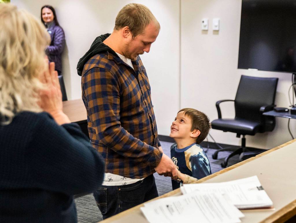 Ryker Moratti looks up at his dad Shaun Moratti and smiles after his adoption is made official during Adoption Day at the Snohomish County Courthouse on Friday, in Everett. (Olivia Vanni / The Herald)