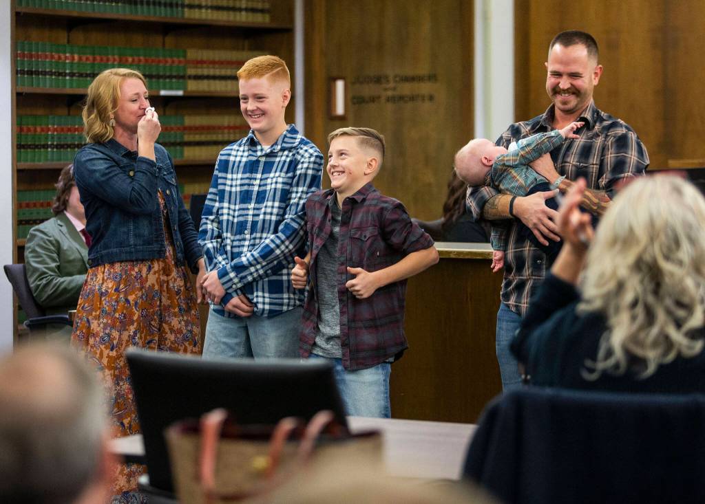 Heather Chadwick, left to right, Kypton Chadwick, Landry Chadwick and Ryan Chadwick smile and laugh after their adoption of Caysen Chadwick is made official during Adoption Day at the Snohomish County Courthouse on Friday, in Everett. (Olivia Vanni / The Herald)