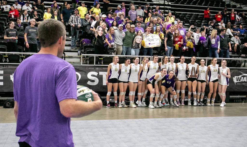 Head coach Kyle Hoglund, left, watches as the Lake Stevens team and fans celebrate their second place finish against Graham-Kapowsin during the WIAA state volleyball championship on Saturday, Nov. 19, 2022, at the Yakima Valley SunDome. (TJ Mullinax/ For The Herald)
