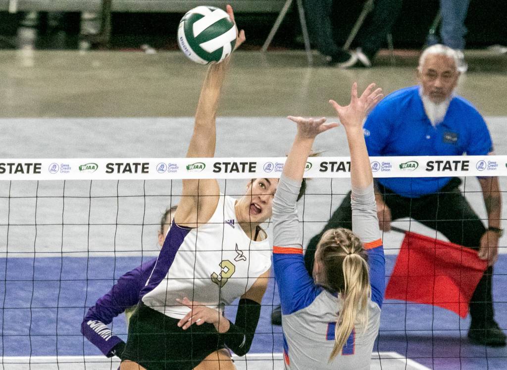 Lake Stevens Laura Eichert (3) spikes past Graham-Kapowsins Grace Peterson (4) during the WIAA state volleyball championship on Saturday, Nov. 19, 2022, at the Yakima Valley SunDome in Yakima. (TJ Mullinax/ For The Herald)