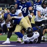 Washington running back Cameron Davis scores a touchdown against Colorado linebacker Josh Chandler-Semedo, second from left, and defensive back Trevor Woods during the first half of an NCAA college football game, Saturday, Nov. 19, 2022, in Seattle. (AP Photo/Stephen Brashear)