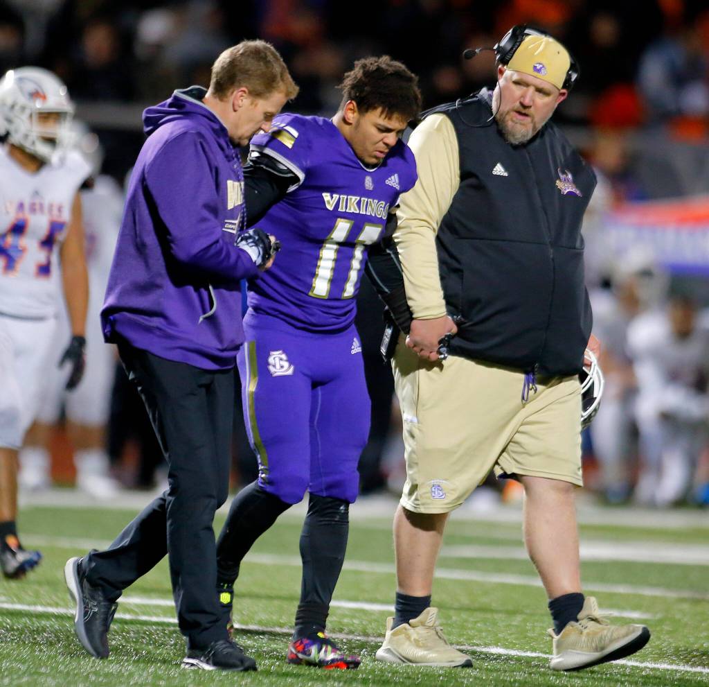 Lake Stevens Jayden Limar is helped off the field after being tended to by medical staff during the 4A semifinal against Graham-Kapowsin on Saturday, Nov. 26, 2022, at Lake Stevens High School in Lake Stevens, Washington. Limar had his ankle taped and was up on the sideline, but did not reenter the game. (Ryan Berry / The Herald)