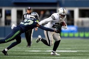 Las Vegas Raiders running back Josh Jacobs (28) runs around Seattle Seahawks cornerback Tariq Woolen (27) during the first half of Sundays game in Seattle. (AP Photo/Caean Couto)