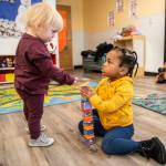 Dakota, 1, left, hands a toy wrench to Khalil, 3, during pick up time at Tomorrows Hope Child Development Center on Nov. 23 in Everett. (Olivia Vanni / The Herald)