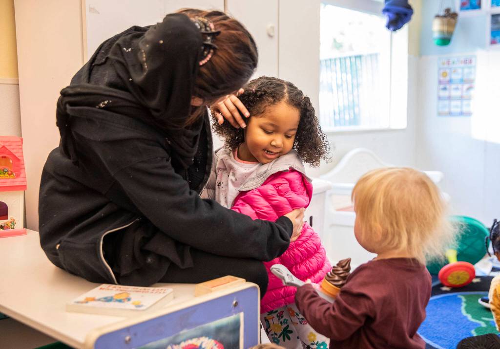 Katie, 3, hugs one of her teachers at Tomorrows Hope Child Development Center in Everett. (Olivia Vanni / The Herald)