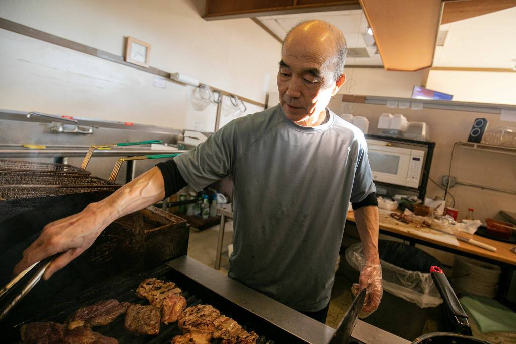 Toshihiro Kasahara works the grill on Jan. 26, 2022, at Toshis Teriyaki in Mill Creek. (Ryan Berry / The Herald)