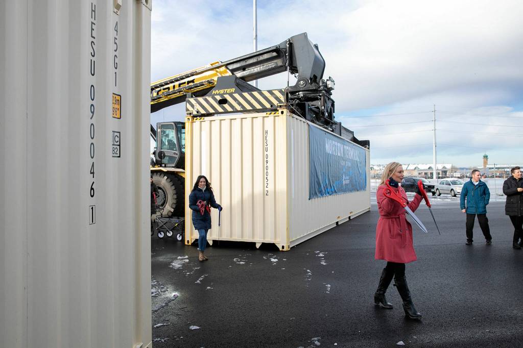 Lisa Lefeber, right, CEO at the Port of Everett, begins handing out oversized scissors for a ribbon cutting during the dedication of the new Norton Terminal on Thursday, Dec. 1, 2022, at the Port of Everett in Everett, Washington. (Ryan Berry / The Herald)