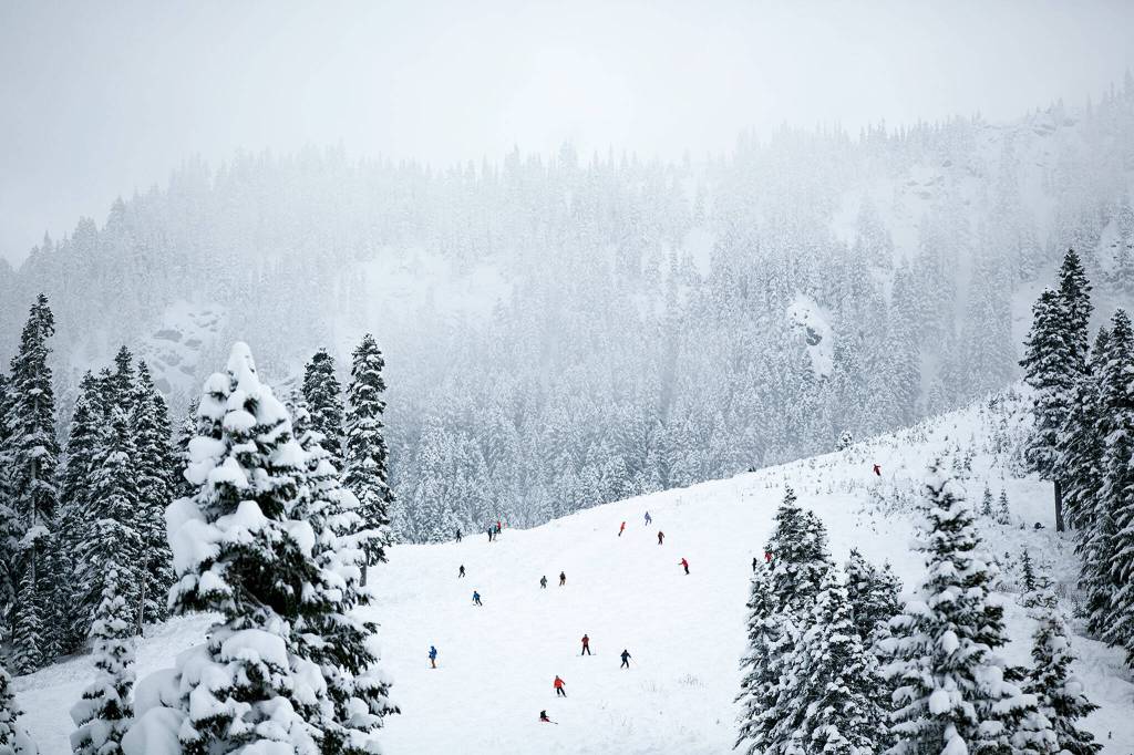 Snow lovers dot the hillside as clouds hang low. (Ryan Berry / The Herald)