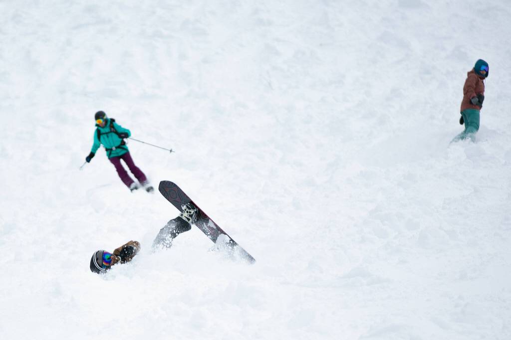 A snowboarder wipes out before getting right back up and finishing the run. (Ryan Berry / The Herald)