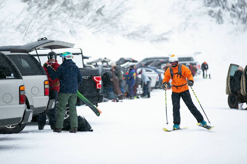 A man skis through the parking lot on his way to the mountain. (Ryan Berry / The Herald)