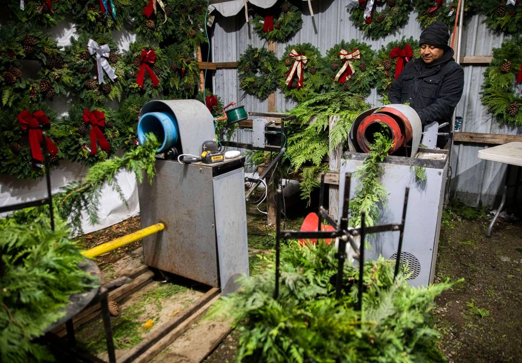 Hector Rodriguez runs the garland wrapping machine on Dec. 5, in Monroe. (Olivia Vanni / The Herald)