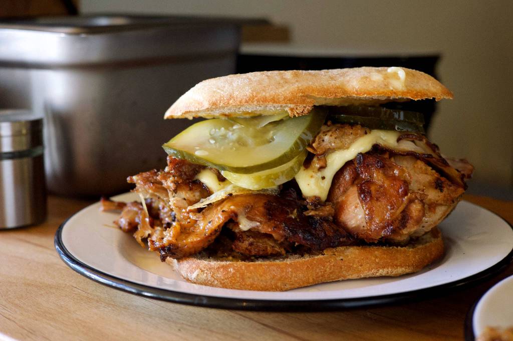 The Midnight Cuban sandwich is Maize & Barleys PNW take on a Miami classic: chunks of house-smoked, slow roasted pork shoulder and loin, white cheese, house pickles, mustard and vegan aioli practically burst out of thin slices of ciabatta. (Photo courtesy of Venus Forteza).