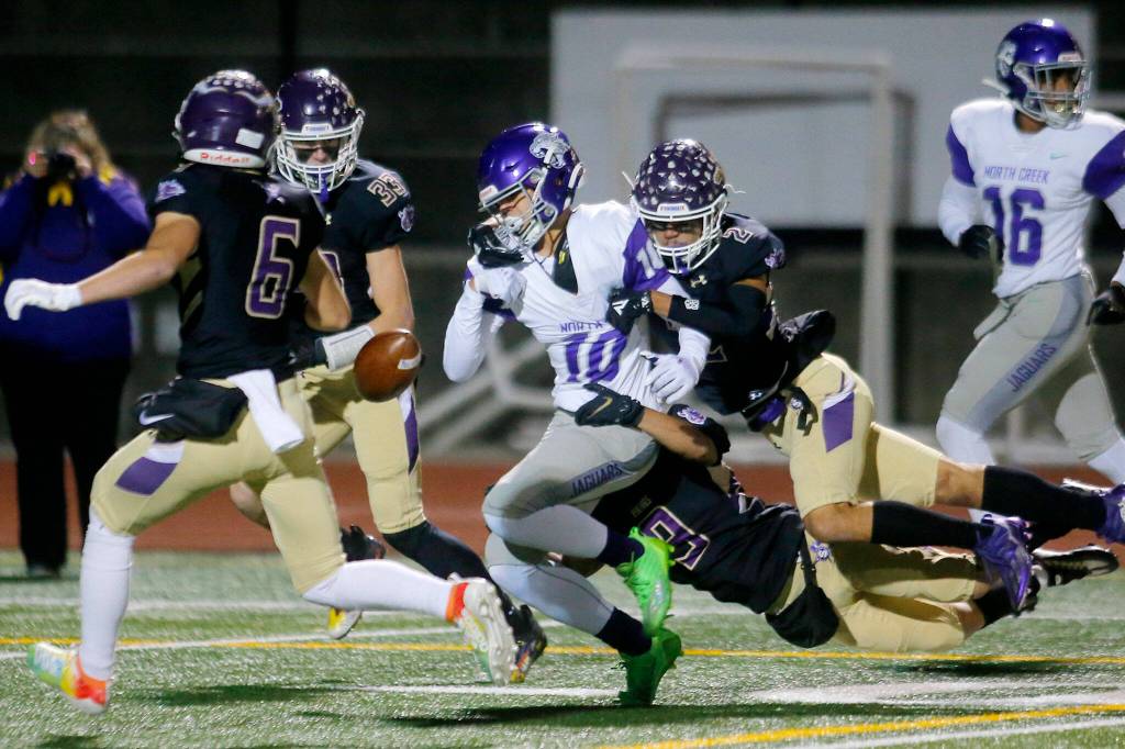 Lake Stevens defenders Paul Varela and Steven Lee Jr. combine on a tackle and force a fumble that was recovered by Lake Stevens during a playoff game against North Creek on Friday, Nov. 11, 2022, at Lake Stevens High School in Lake Stevens, Washington. (Ryan Berry / The Herald)