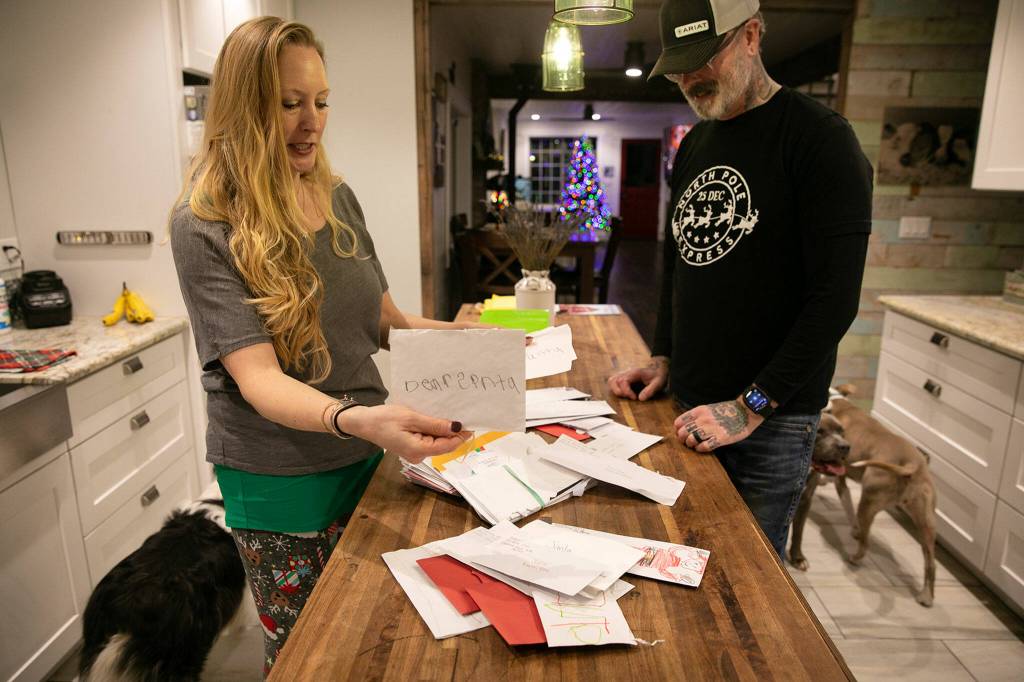 Lena and Brian Schultz sift through a small number of the hundreds of letters to Santa that theyve handled over the years at Living Aloha Farm in Lake Stevens. (Ryan Berry / The Herald)