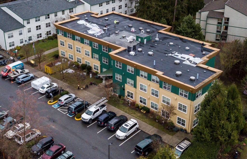 People work on the roof of the Stilly Valley Senior Center on Thursday, in Arlington. (Olivia Vanni / The Herald)