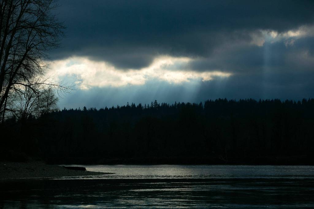 Streaks of light shine through the clouds over the Snohomish River on Dec. 14, at Bob Heirman Wildlife Park at Thomas Eddy, in Snohomish. (Ryan Berry / The Herald)