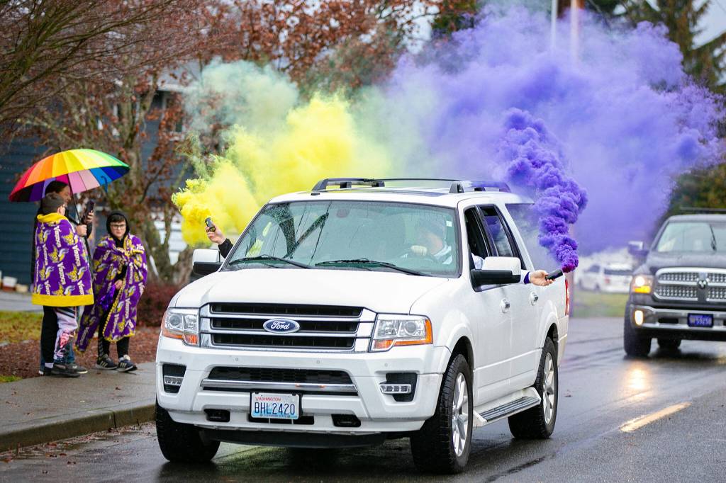 Purple and gold smoke billows from a car during Lake Stevens High Schools 4A football championship parade Saturday, Dec. 10, 2022, in Lake Stevens, Washington. (Ryan Berry / The Herald)