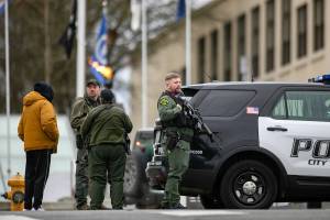 Armed police wait outside the Snohomish County Superior Courthouse while dealing with an armed person inside Monday, Dec. 12, 2022, in downtown Everett, Washington. (Ryan Berry / The Herald)