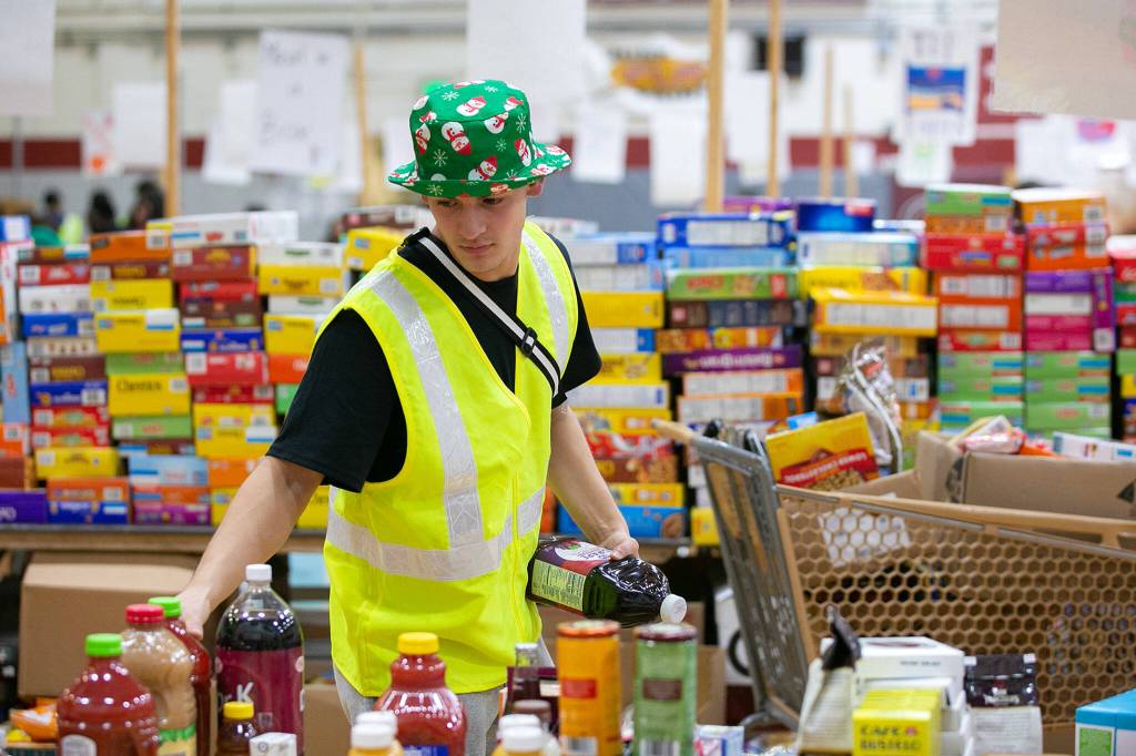 Zach Lopez, a junior at Cascade, finishes up packing a box for a family in need during Cascades annual holiday food drive Wednesday, Dec. 14, at Cascade High School in Everett. (Ryan Berry / The Herald)