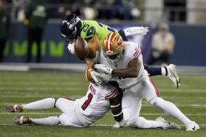 Seattle Seahawks running back Travis Homer (25) fumbles while being hit by San Francisco 49ers linebacker Dre Greenlaw, right, and cornerback Jimmie Ward (1) during the first half of Thursday nights game in Seattle. (AP Photo/Stephen Brashear)