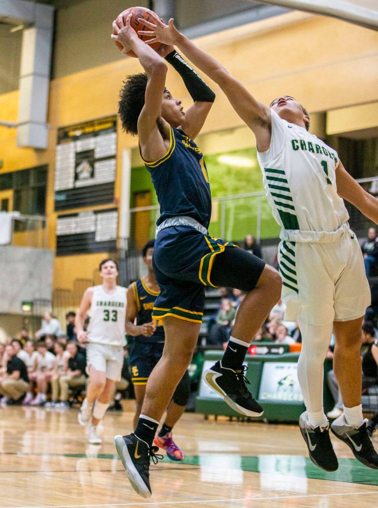 Shorecrests Keanie Silimon leaps to try and make a layup over the arm of Marysville Getchells Mariano Palacol during the game on Friday, Dec. 16, 2022 in Marysville, Washington. (Olivia Vanni / The Herald)
