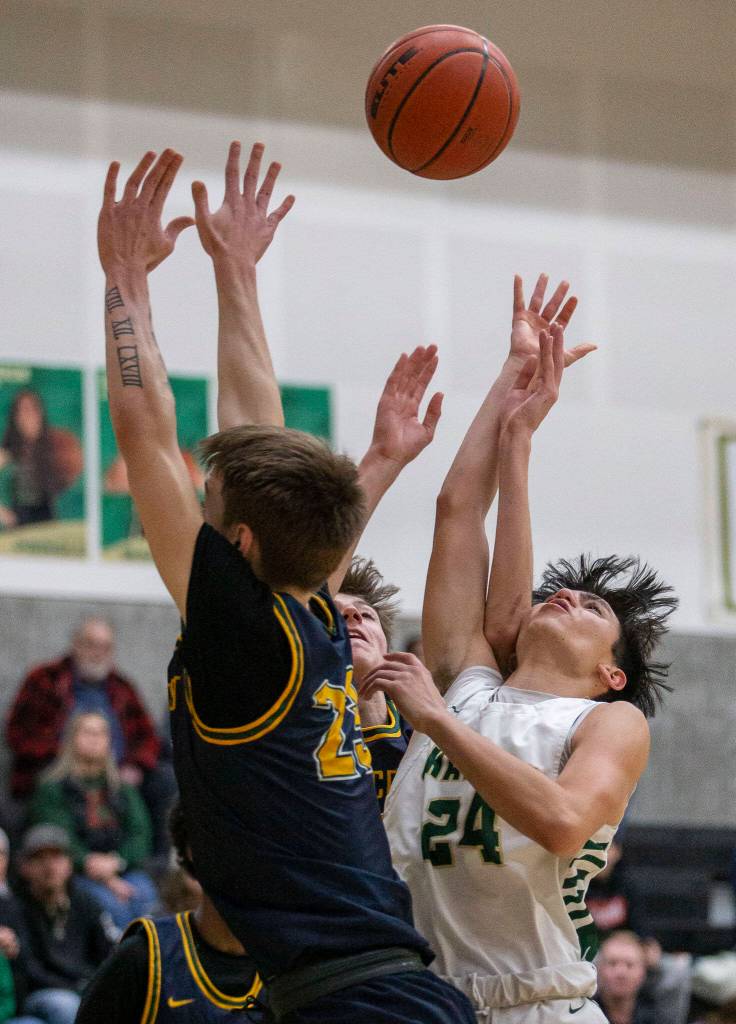 Shorecrest and Marysville Getchell players leap in the air for a rebound during the game on Friday, Dec. 16, 2022 in Marysville, Washington. (Olivia Vanni / The Herald)