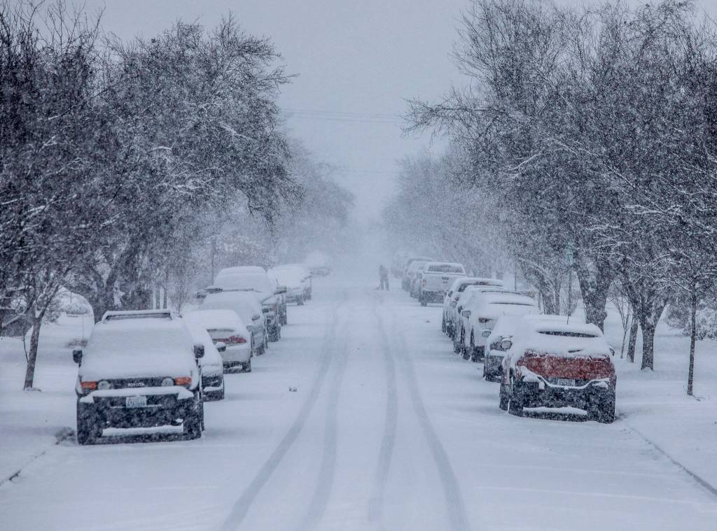 A person shovels snow away from their car tires as snow falls on Tuesday, in Everett. (Olivia Vanni / The Herald)