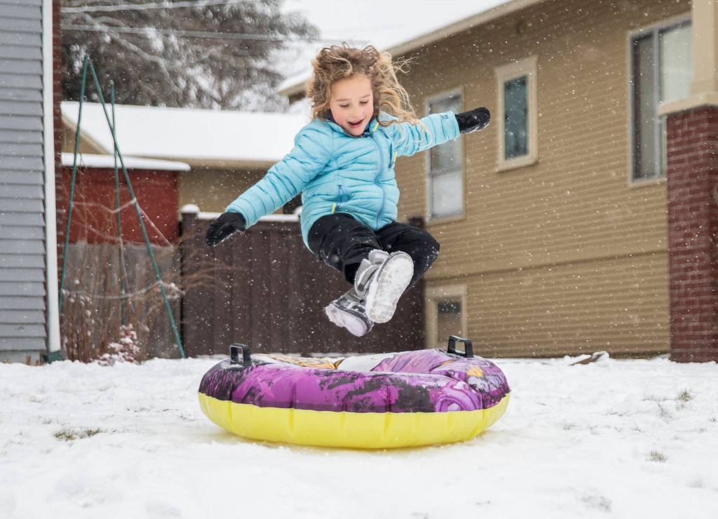 Halle Lucas-Roberts, 6, leaps onto her tube while sledding in front of her home on Tuesday, in Everett. (Olivia Vanni / The Herald)