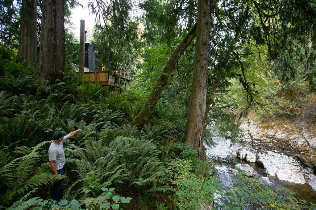 Co-owner Andy Whitcomb stands below Cabin 3 and above a trickling Canyon Creek at Canyon Creek Cabins on Sep. 23, in Granite Falls. (Ryan Berry / The Herald)