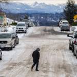 A pedestrian navigates compact snow and ice while crossing the street on Thursday, in Everett. (Olivia Vanni / The Herald)