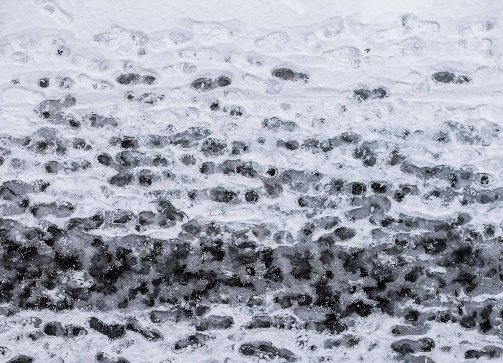 Ice freezes over footprints along Rockefeller Avenue on Thursday, Dec. 22, 2022 in Everett, Washington. (Olivia Vanni / The Herald)