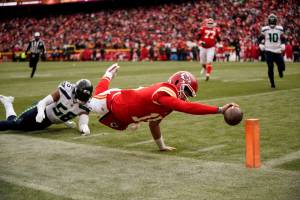 Kansas City Chiefs quarterback Patrick Mahomes (15) dives for the end zone pylon to score a touchdown as Seattle Seahawks linebacker Jordyn Brooks (56) defends during the second half of an NFL football game Saturday, Dec. 24, 2022, in Kansas City, Mo. (AP Photo/Charlie Riedel)