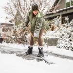 Carly McGinn shovels the sidewalk in front of her home as snow falls on Tuesday, Dec. 20, 2022 in Everett, Washington. (Olivia Vanni / The Herald)