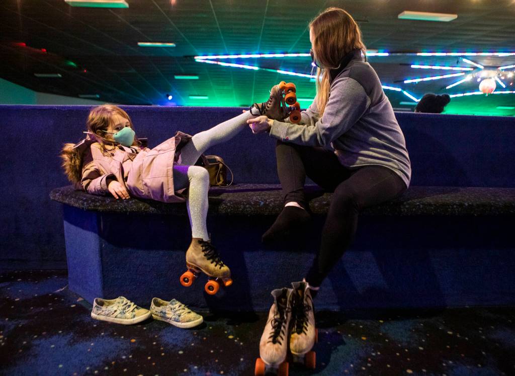 Courtney Simons, right, helps her daughter Whitaker, 5, get her skates on before heading out to the rink at Everett Skate Deck on Thursday, March 3, 2022 in Everett, Washington. (Olivia Vanni / The Herald)