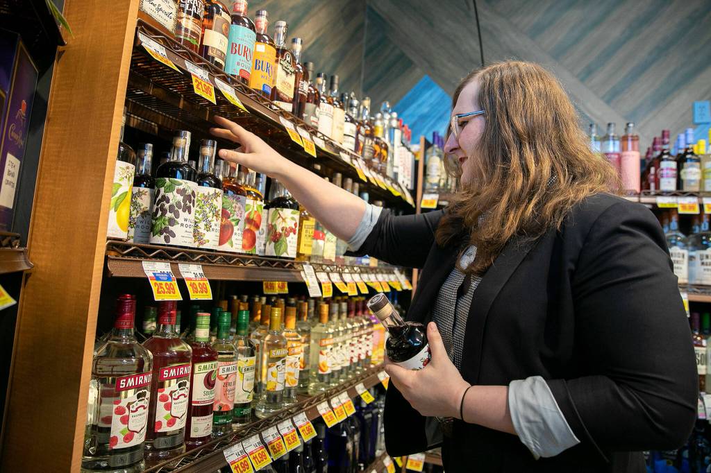 Luin Loeffelbein, wine steward at the Evergreen QFC, pulls a few bottles off the shelves on Oct. 13, 2022, in Everett. (Ryan Berry / The Herald)