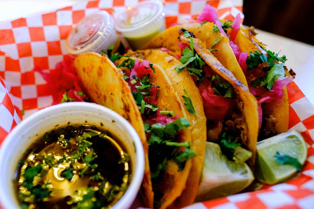 The queso birria tacos at El Mariachi call for slow cooked brisket, melty cheese sandwiched between two corn tortillas, a shower of cilantro and bright pink pickled onions, and a bowl of consomé. (Taylor Goebel / The Herald)