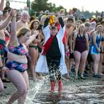 Edith Farrar watches as people begin to run into the ocean, perhaps a moment too early, during the 2023 Edmonds Polar Bear Plunge on Sunday, Jan. 1, 2023, at Bracketts Landing in Edmonds, Washington. (Ryan Berry / The Herald)
