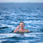Caroline Bernatek, 12, gives a thumbs-up from the roughly 46-degree Pacific water as she tries to see how long she can last during the 2023 Edmonds Polar Bear Plunge on Sunday, Jan. 1, 2023, at Bracketts Landing in Edmonds, Washington. Bernatek has a running bet with her cousin and receives a dollar for every minute spent in the frigid water. (Ryan Berry / The Herald)