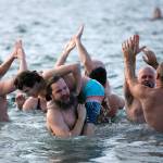 A group of plungers celebrate their bravery during the 2023 Edmonds Polar Bear Plunge on Sunday, Jan. 1, 2023, at Bracketts Landing in Edmonds, Washington. (Ryan Berry / The Herald)