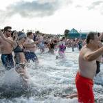 People sprint into the frigid waters of the Puget Sound to help ring in the new year during the 2023 Edmonds Polar Bear Plunge on Sunday, Jan. 1, 2023, at Bracketts Landing in Edmonds, Washington. (Ryan Berry / The Herald)