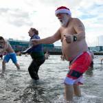 Santa Claus heads for the shore after taking a dip in the Sound during the 2023 Edmonds Polar Bear Plunge on Sunday, Jan. 1, 2023, at Bracketts Landing in Edmonds, Washington. (Ryan Berry / The Herald)