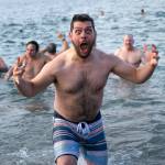 A plunger emerges from the water hyped up and freezing during the 2023 Edmonds Polar Bear Plunge on Sunday, Jan. 1, 2023, at Bracketts Landing in Edmonds, Washington. (Ryan Berry / The Herald)