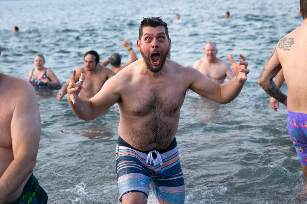 A plunger emerges from the water hyped up and freezing during the 2023 Edmonds Polar Bear Plunge on Sunday, Jan. 1, 2023, at Bracketts Landing in Edmonds, Washington. (Ryan Berry / The Herald)