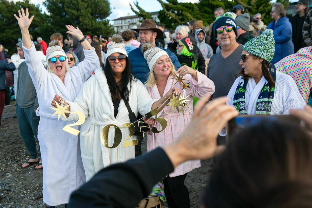 A group of plungers take a photo celebrating the new year before heading into the water during the 2023 Edmonds Polar Bear Plunge on Sunday, Jan. 1, 2023, at Bracketts Landing in Edmonds, Washington. (Ryan Berry / The Herald)
