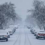 A person shovels snow away from their car tires as snow falls on Tuesday, Dec. 20, 2022 in Everett, Washington. (Olivia Vanni / The Herald)