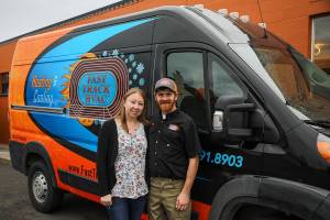 Patricia Cairus, 36, left, and Nick Cairus, 38, right, pose for a photo by one of their vans at Fast Track Hvac in Stanwood on Monday, Jan. 9, 2023. Nick Cairus and Patricia Cairus lost their housing in the recession and were homeless for a number of years. They started a successful HVAC company during the pandemic in a former newspaper printing building.  (Annie Barker / The Herald)
