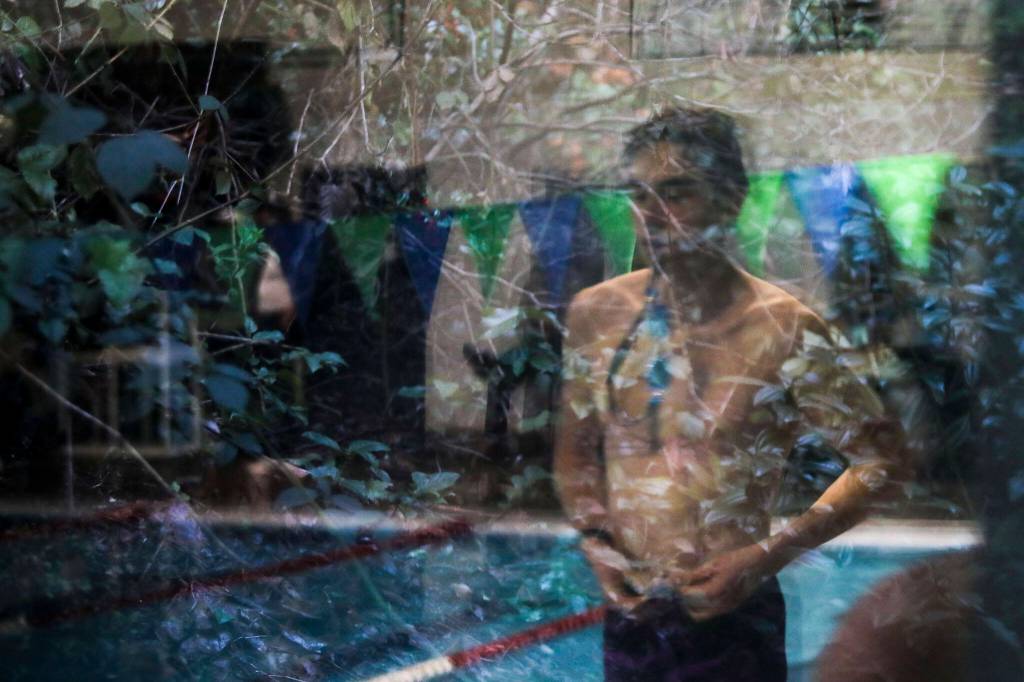 A reflection of a swimmer preparing to race during the Jackson vs. Kamiak boys swim and dive meet at West Coast Aquatics in Mill Creek, Washington on Tuesday Jan. 10, 2023. (Annie Barker / The Herald)