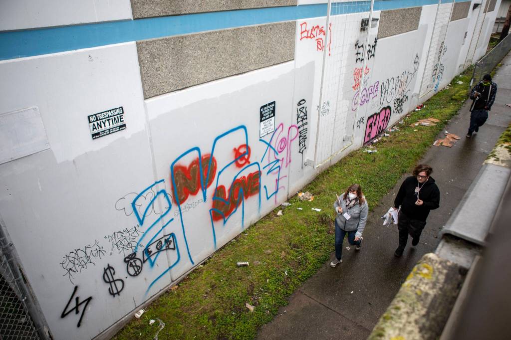 Point-in-time count volunteers walk under an overpass where several people live in cars and RVs during a point-in-time count of people facing homelessness on Tuesday in Everett. (Annie Barker / The Herald)