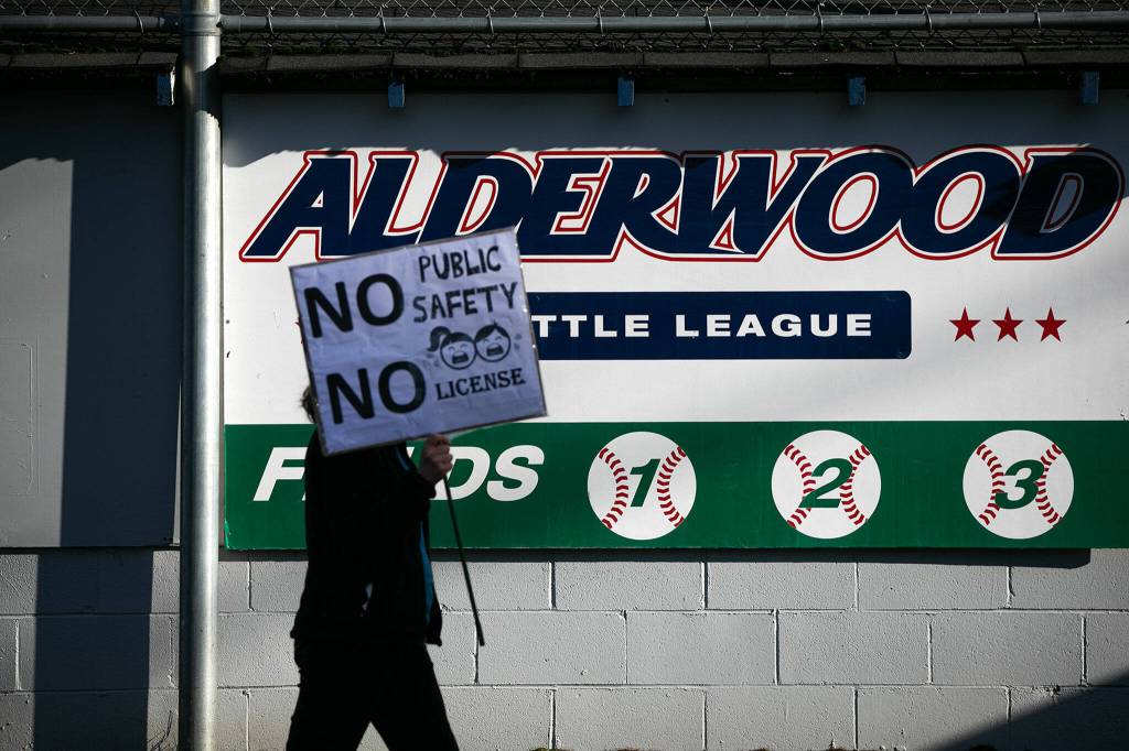 A protestor walks past a Little League ball field during a protest against the opening of a nearby methadone clinic on Saturday, Jan. 14, 2023, in Lynnwood, Washington. (Ryan Berry / The Herald)